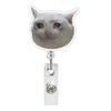 A silver retractable ID badge holder with a crocodile clip attached to a clear badge holder featuring a cat face charm.