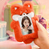 A hand holds an orange fox plush photocard holder with a white inner frame, displaying a woman's face.