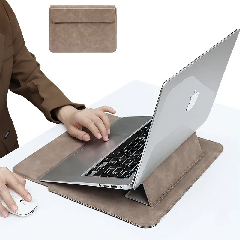 Ein silberner Laptop liegt auf einer braunen Lederhülle neben einer passenden rechteckigen Tasche.