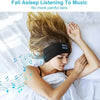 A woman is sleeping with a black headband device on her forehead, listening to music.