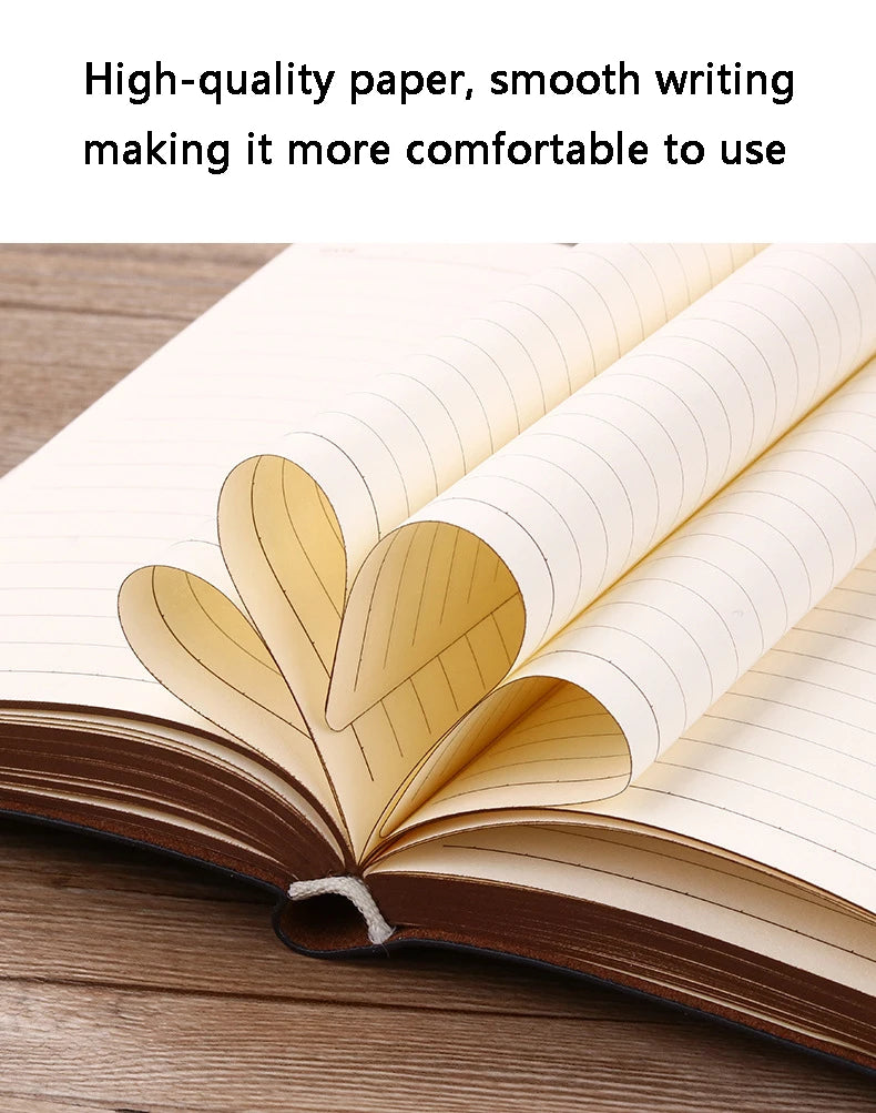 An open notebook with lined pages showing a decorative leaf pattern on the cover, resting on a wooden surface.