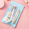 A light blue plastic case holds a set of cute cartoon school stationery including pens and an eraser.