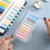 A hand holds a sheet of transparent self-adhesive sticky notes displaying various pastel colors for reading and annotation.