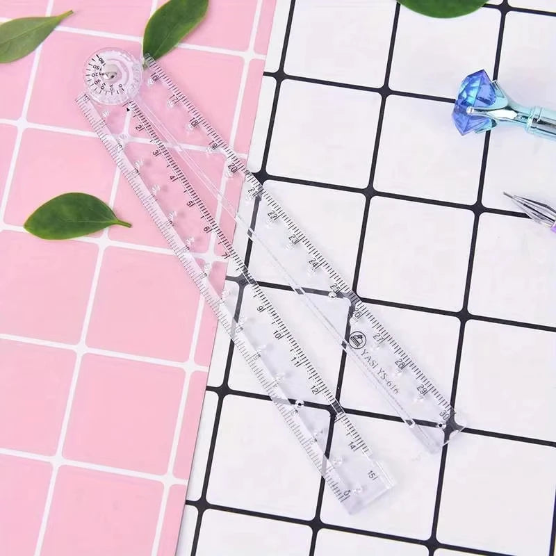 A set of precision folding transparent rulers and a blue glass tool are displayed on a pink and white grid background.