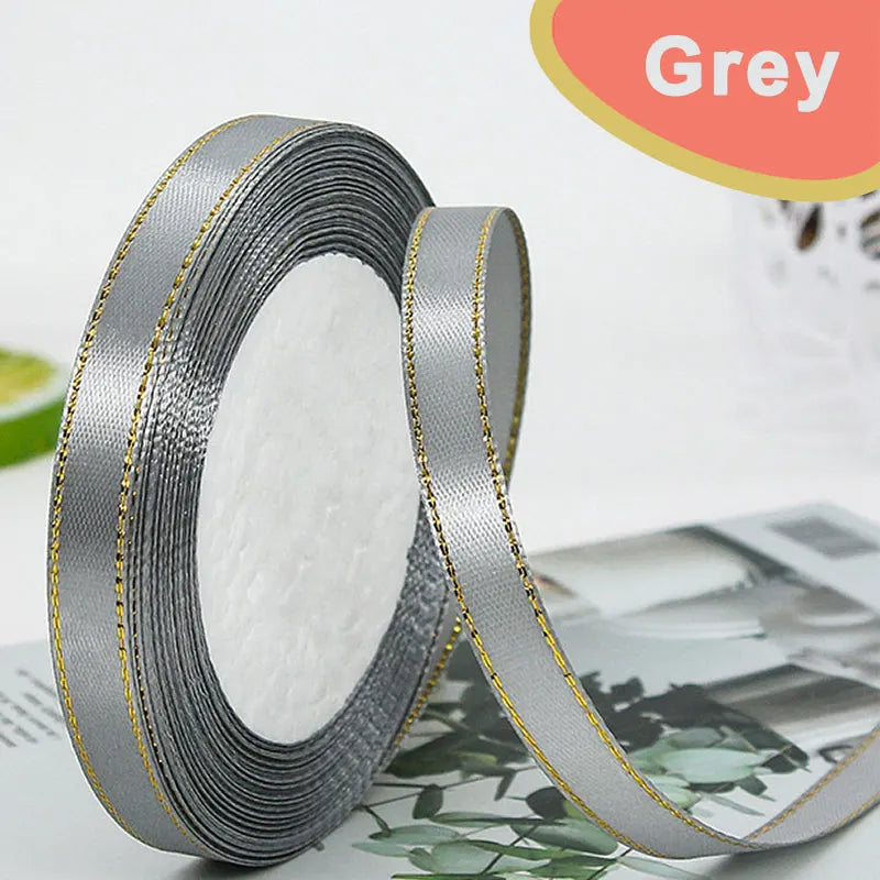 Roll of grey satin ribbon with gold edge, showing the wide fabric and texture.
