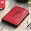 A red retro PU leather pocket notebook with embossed circular design lying on a wooden surface.
