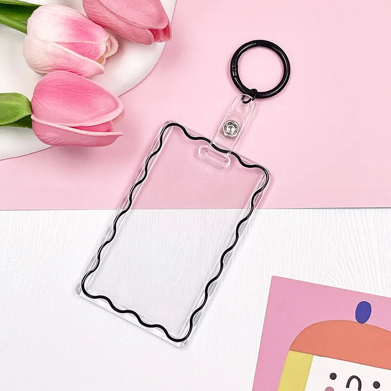 Clear acrylic card holder with a black keychain attached, set against a pink background.