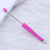 A pink DIY beadable pen with a silver tip and purple cap resting on a white, fluffy surface.