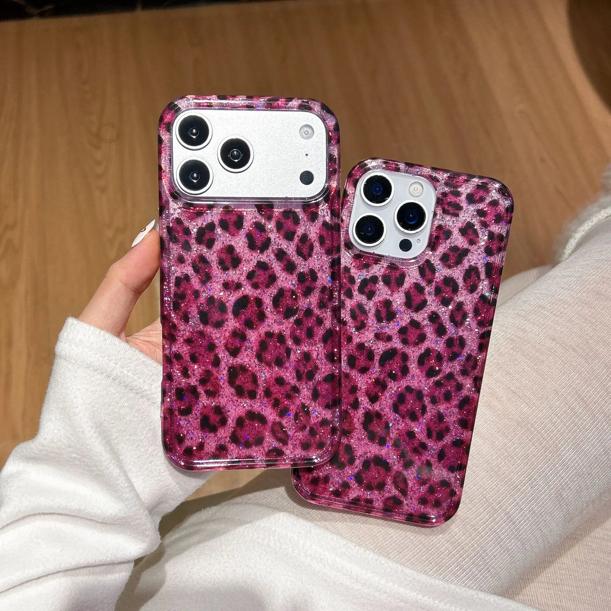 A hand holds a pink leopard print sequin shockproof phone case for an iPhone.