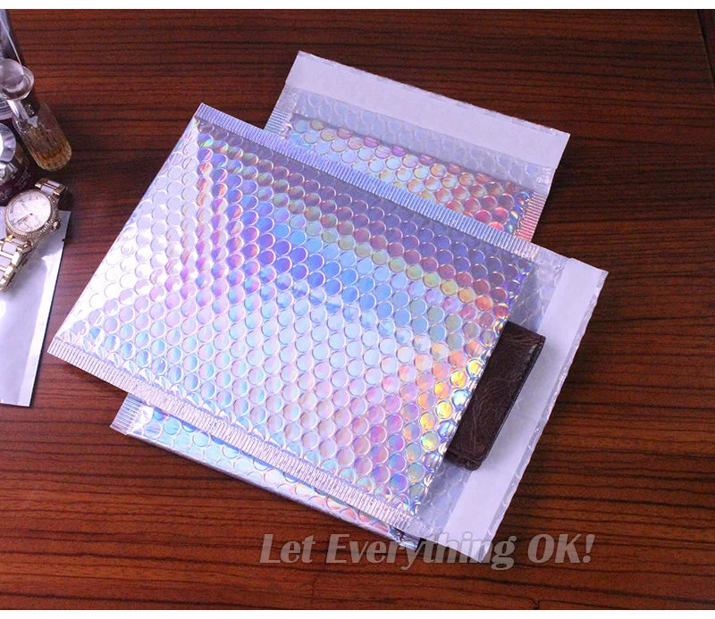 Rainbow foil bubble mailers stacked on a wooden surface.