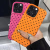 A hand holds an orange polka dot textured phone case, featuring a pink version alongside it.