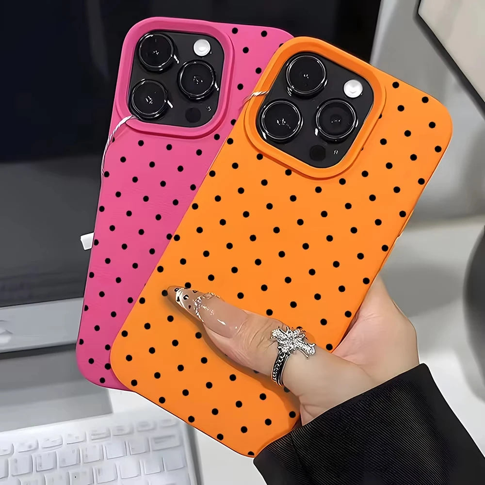 A hand holds an orange polka dot textured phone case, featuring a pink version alongside it.