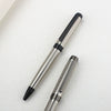 A close-up view of a premium metal ballpoint pen with a silver finish and black accents resting on a white surface.