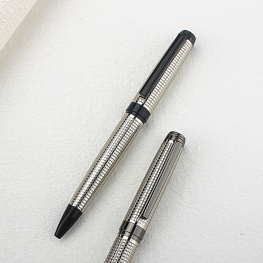 A close-up view of a premium metal ballpoint pen with a silver finish and black accents resting on a white surface.