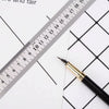 A black pen is placed next to a ruler marked in millimeters on white paper.