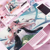 A pink mouse pad featuring an anime girl illustration with pink hair and a bow, placed on a desk.
