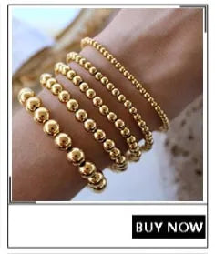 A close-up of a hand wearing multiple strands of gold-plated shell pearl beaded bracelets.