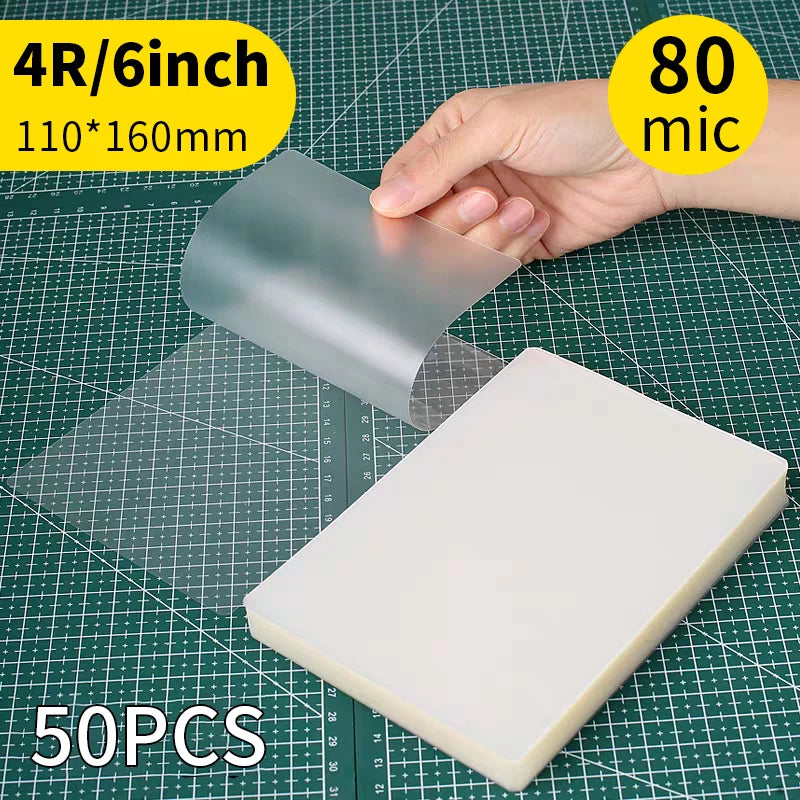 A hand is holding a clear thermal laminating pouch, showing its size and material against a grid background.