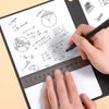 A hand is writing mathematical formulas and diagrams on a white notebook page using a black pen and a ruler.