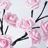 Pink artificial roses growing on black branches used as a decorative LED night light.