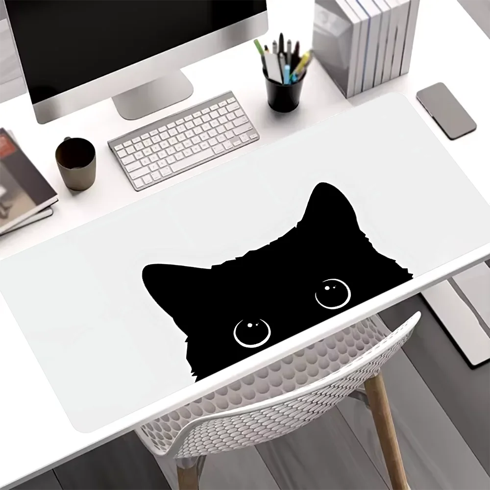 A black silhouette of a cat's head is printed on a white mouse pad placed on a desk.