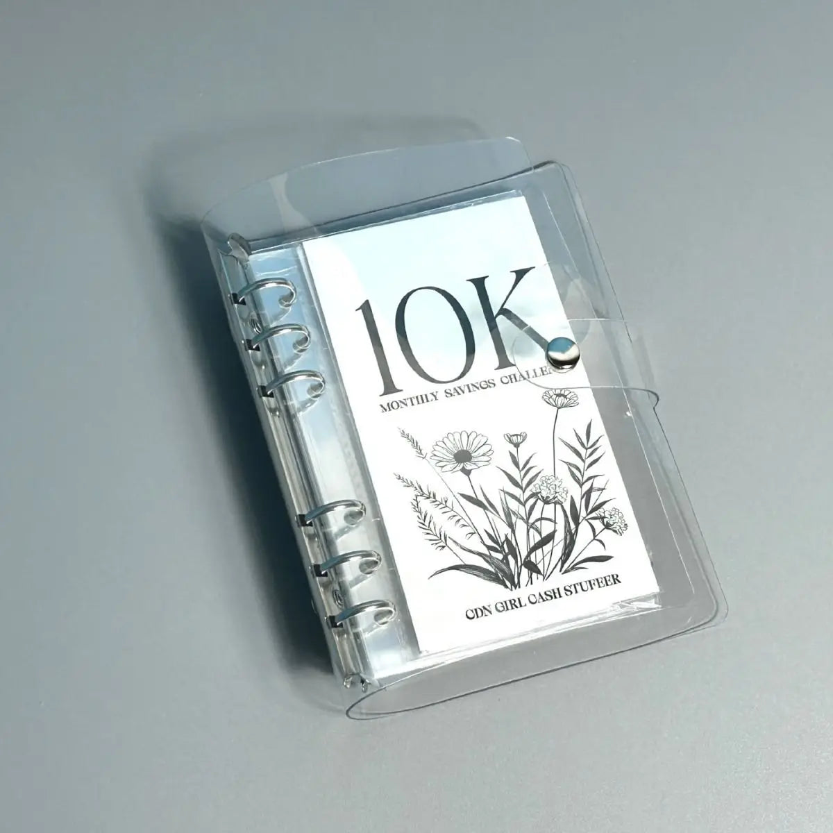 A clear plastic money clip shows the text 10K monthly savings challenge and the name Cin Girl Cash Stufeer