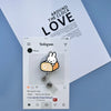A white Instagram post featuring a Miffy rabbit badge reel attached to a clear clip, set against a light blue background.