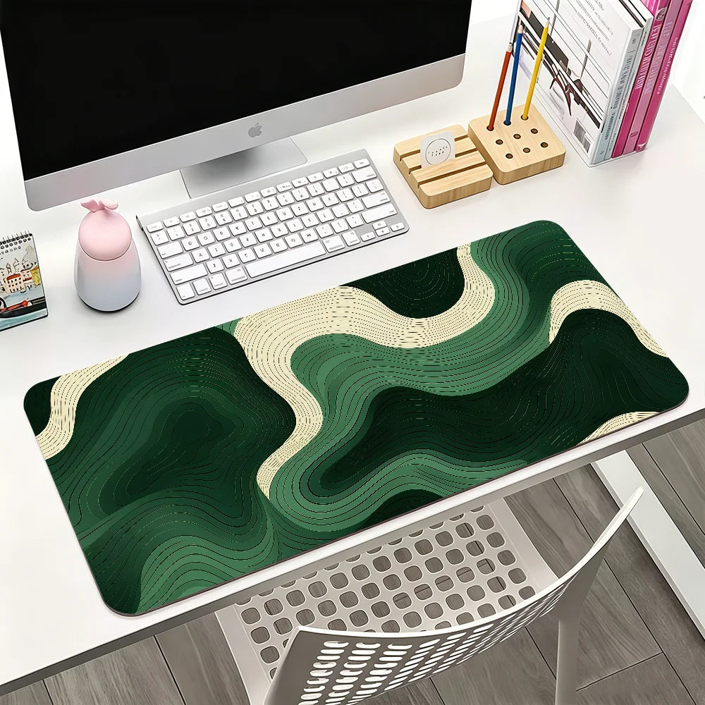 A dark green mouse pad with abstract wavy patterns is displayed on a white desk next to a computer and stationery.
