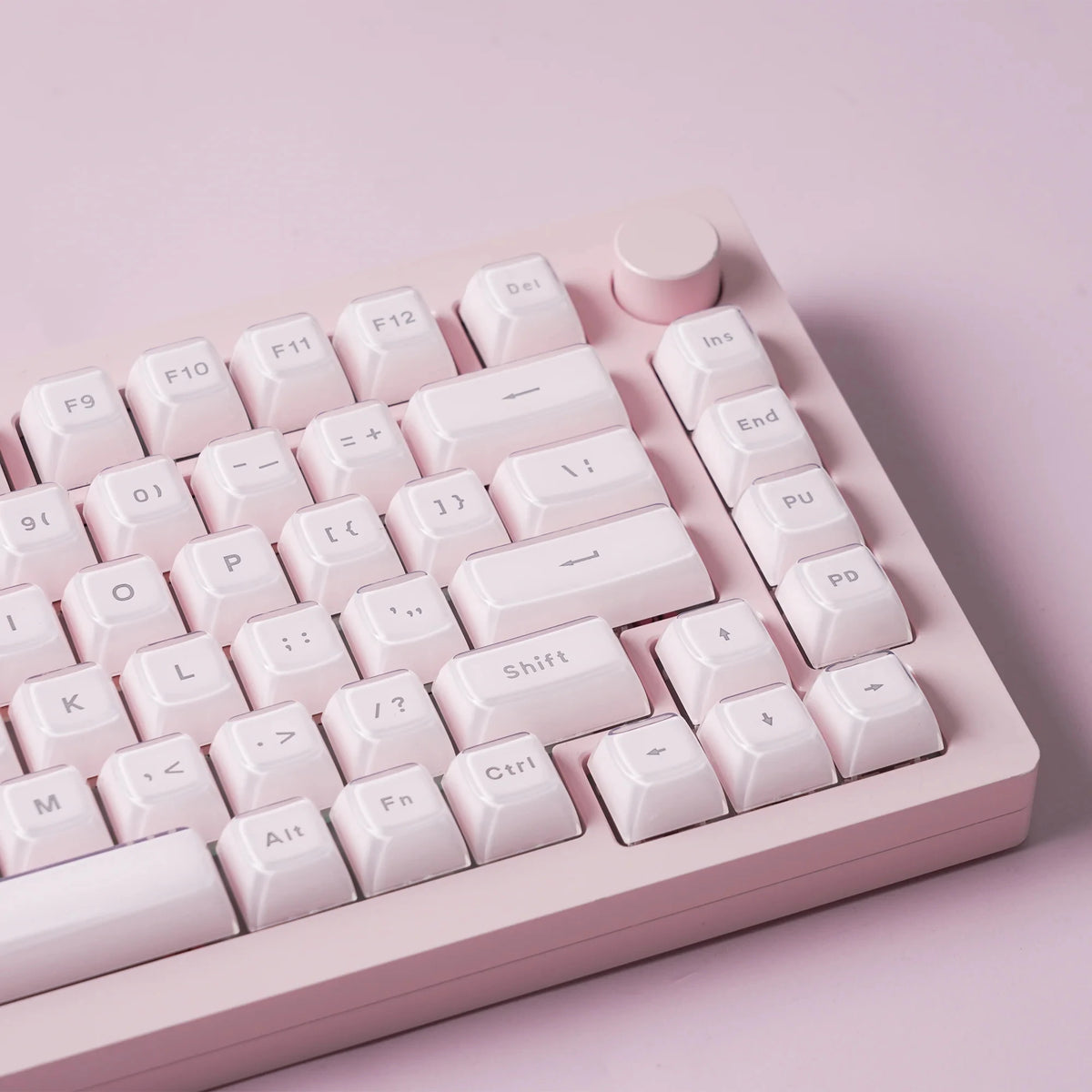 A close-up view of a translucent pink jelly keycaps set for mechanical keyboards arranged on a light pink plastic board.