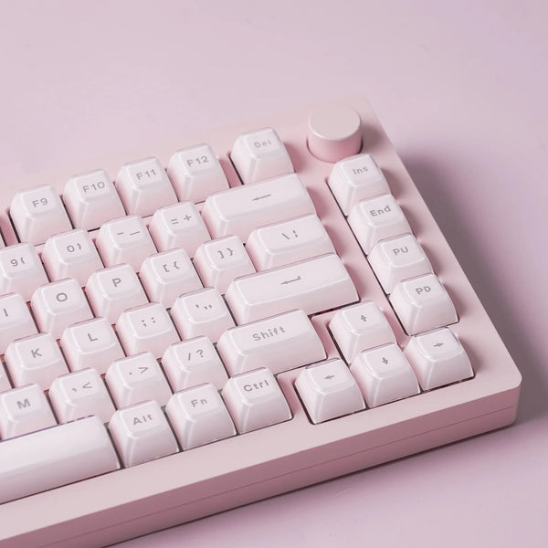 A close-up view of a translucent pink jelly keycaps set for mechanical keyboards arranged on a light pink plastic board.