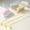 A set of colorful mini multi-hole punches for notebooks and planners displayed on a white sheet of paper.