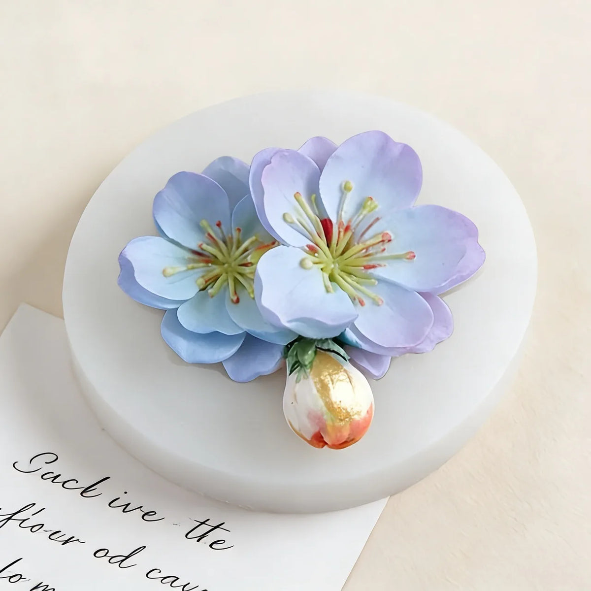 A light blue and purple flower arrangement displayed on a white circular card.