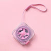 A pink compact retractable measuring tape with a lock is shown against a light pink background.