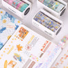 A collection of decorative transparent washi tape rolls in various colors and patterns displayed in open boxes next to a note
