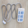 A white extra strong double-sided nano tape dispenser with coiled gray tape and a power cord lying on a light wood surface.