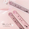 A pink plastic ruler featuring paw prints and cat designs, used for measuring.