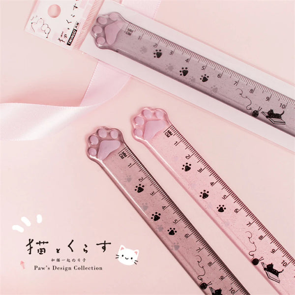 A pink plastic ruler featuring paw prints and cat designs, used for measuring.