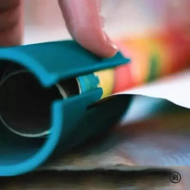 A hand is operating a teal portable mini paper cutting machine to cut paper.