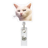 A white cat head cutout attached to a retractable ID badge holder with a crocodile clip.