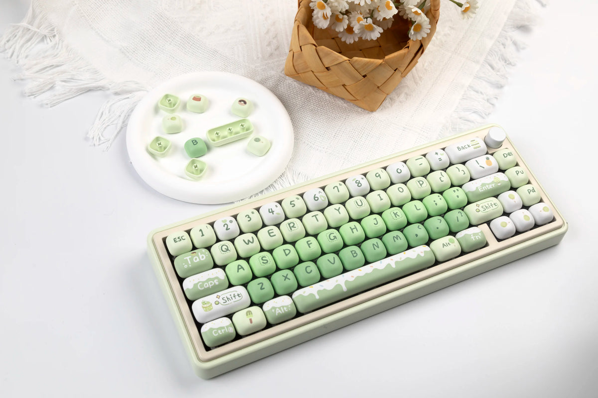 A close-up of a light green mechanical keyboard featuring colorful PBT keycaps and a small set of matching keycaps.