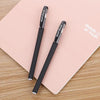 A pair of black gel ink pens labeled TEST 2 are placed on a pink notebook.