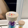 A clear tube filled with colorful plastic rings and a wooden cap, used as a musical instrument.