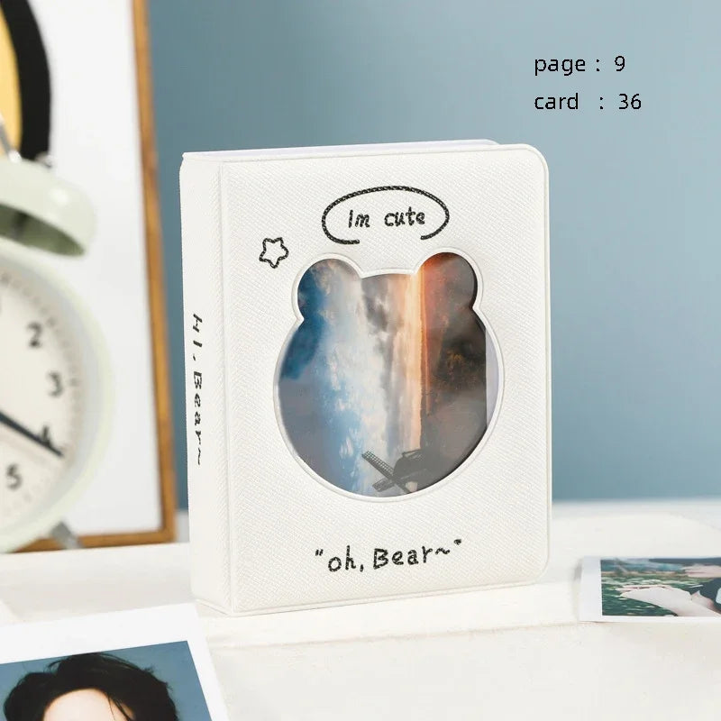 A white photo card binder with a clear window showing a silhouette of a bear against a cloudy sky and sunset.