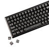 Close-up view of black mechanical keyboard keycaps with carbon fiber texture, showing various function keys and modifiers.