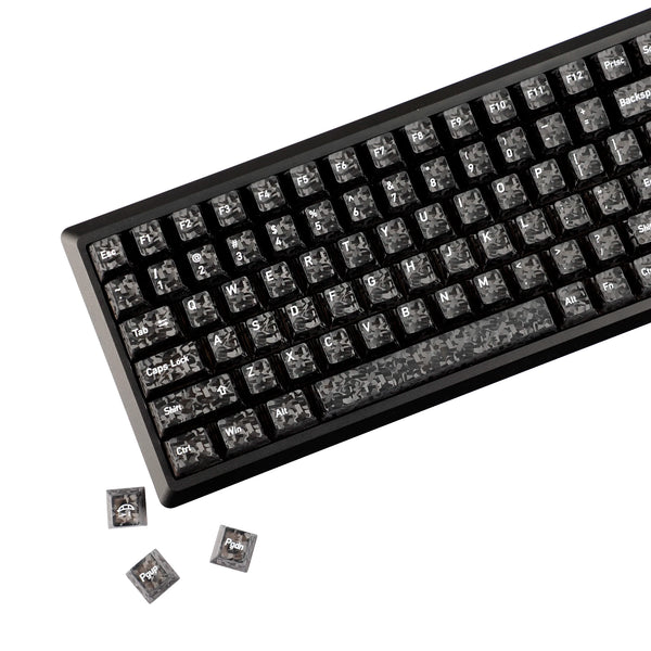 Close-up view of black mechanical keyboard keycaps with carbon fiber texture, showing various function keys and modifiers.