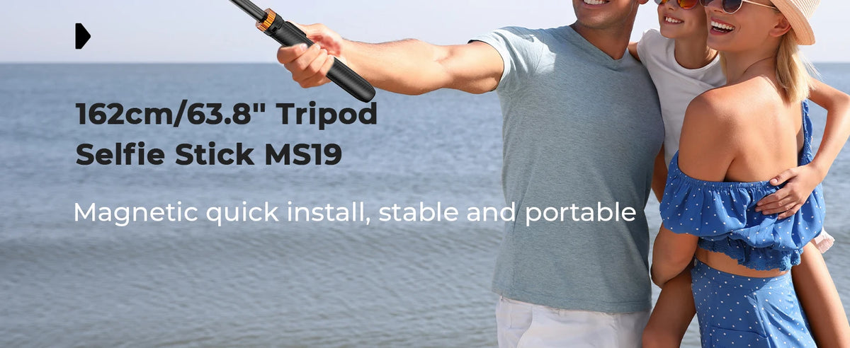 A person holds a magnetic selfie stick tripod for taking photos, with other people visible in the background.