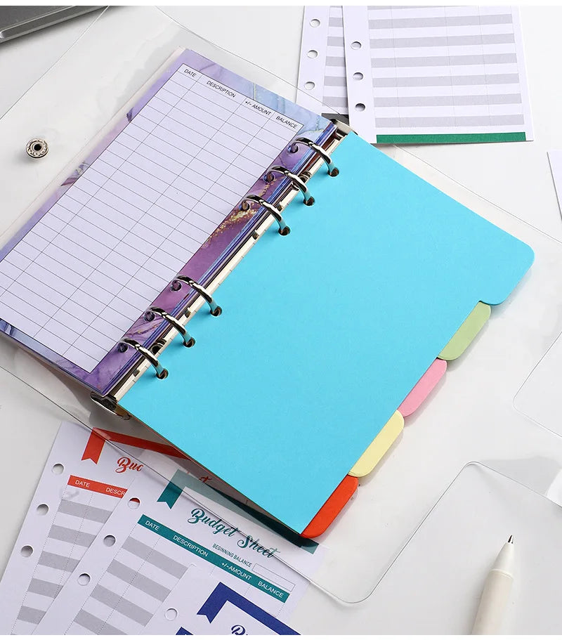 A6 budget planner binder with purple cover, blue sheet, and expense sheets on a white desk.