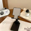 A black adjustable foldable phone and tablet stand resting on a white paper with text.