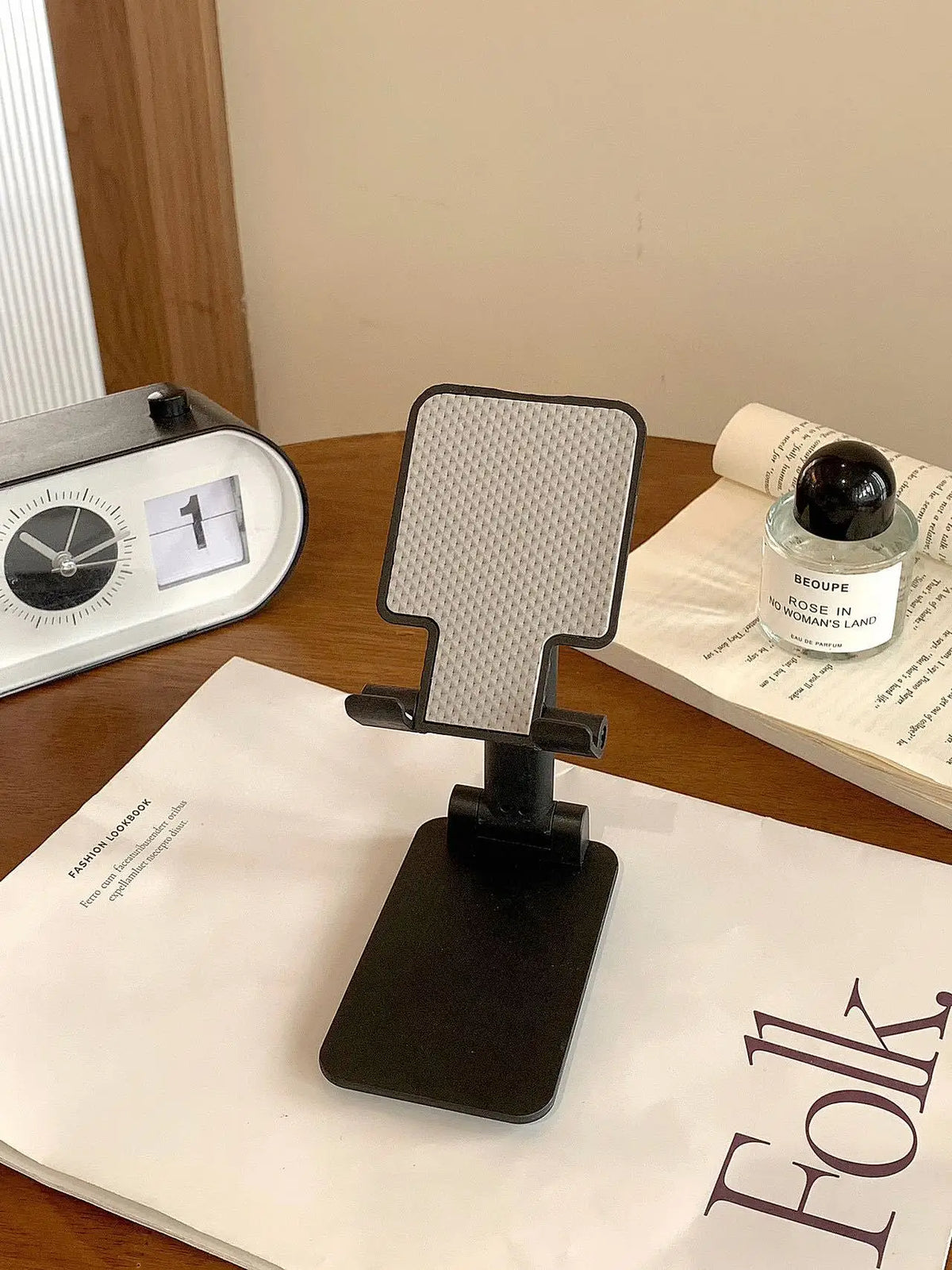 A black adjustable foldable phone and tablet stand resting on a white paper with text.