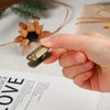 A hand holds a metal beetle binder clip set against a white background.